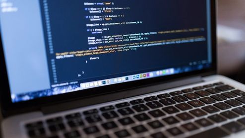 Primer plano de una pantalla de ordenador portátil que muestra líneas de código de programación en un editor con fondo oscuro.
