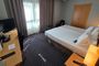 Habitación de hotel con dos camas individuales unidas, escritorio con televisor y armario de madera en Ciudad Real.