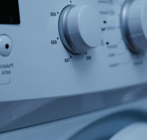 Detalle del panel de control de una lavadora doméstica con diales de temperatura y programas.