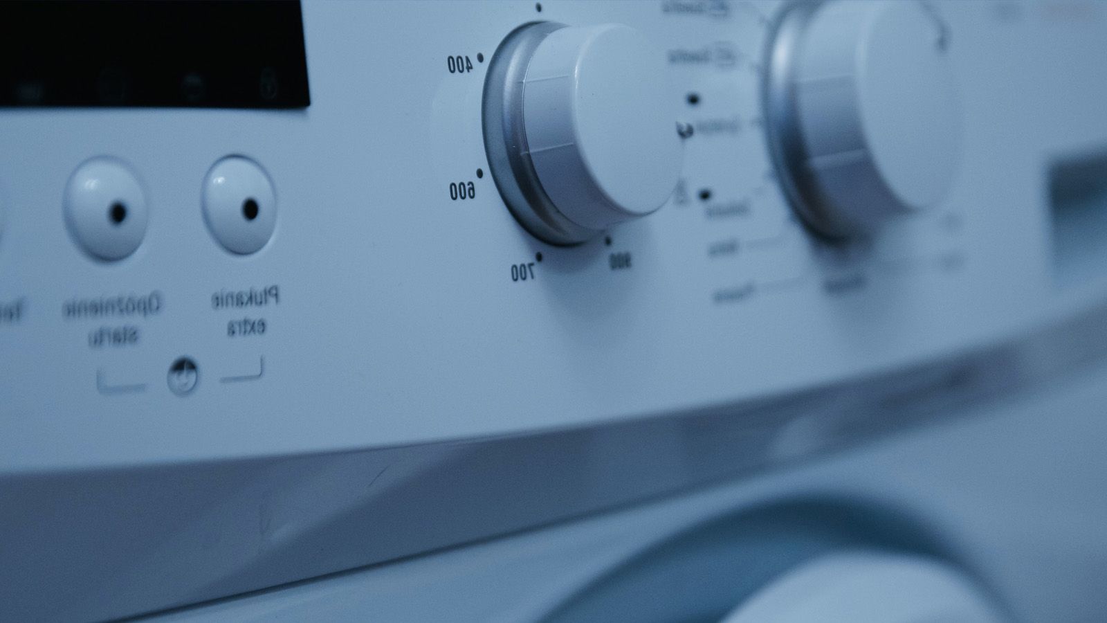 Primer plano del panel de control de una lavadora blanca con diales giratorios y botones de configuración.