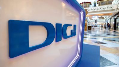 Logotipo de DIGI en letras azules corpóreas sobre un soporte blanco iluminado en un centro comercial.