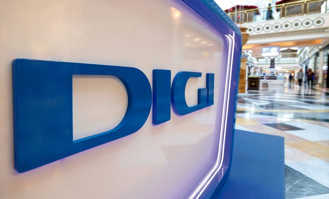 Logotipo de DIGI en letras azules corpóreas sobre un soporte blanco iluminado en un centro comercial.