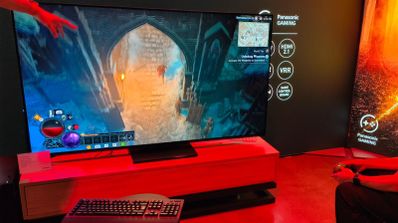 Televisor de gran formato mostrando una partida de videojuego de rol en un entorno de exposición con iluminación roja.