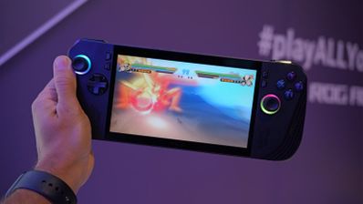 Consola portátil ejecutando un videojuego de lucha con efectos de iluminación RGB en los joysticks.
