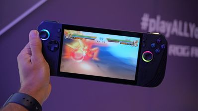 Consola portátil ejecutando un videojuego de lucha con efectos de iluminación RGB en los joysticks.