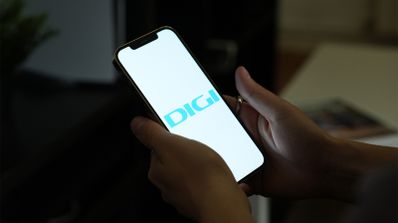 Manos sujetando un teléfono móvil que muestra el logotipo de DIGI en pantalla sobre un fondo blanco.