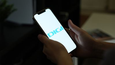 Manos sujetando un teléfono móvil que muestra el logotipo de DIGI en pantalla sobre un fondo blanco.