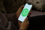 Persona sosteniendo un teléfono móvil con el logotipo de WhatsApp en pantalla.