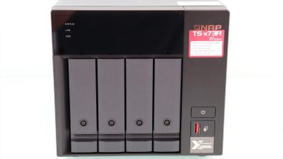 Vista frontal de un servidor NAS QNAP TS-473A con cuatro bahías para discos duros, botones de control y puertos de conexión rápidos.