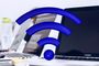 Icono de señal Wi-Fi en color azul superpuesto a varios ordenadores portátiles en una oficina.