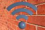 Icono de señal Wi-Fi de color azul sobre una pared de ladrillo rojo.