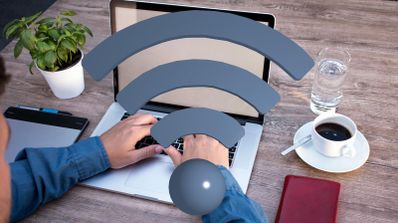 Persona trabajando con un ordenador portátil en una mesa de madera con un icono de señal Wi-Fi superpuesto.
