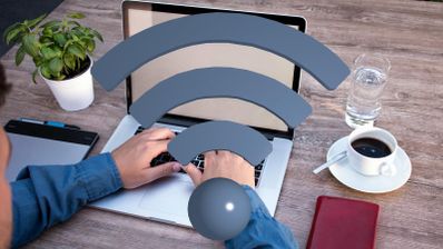 Persona trabajando con un ordenador portátil en una mesa de madera con un icono de señal Wi-Fi superpuesto.