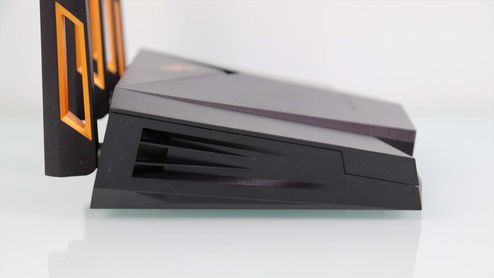 Vista lateral de un router ASUS TUF-AX4200 de color negro con rejillas de ventilación y antenas con detalles en naranja.