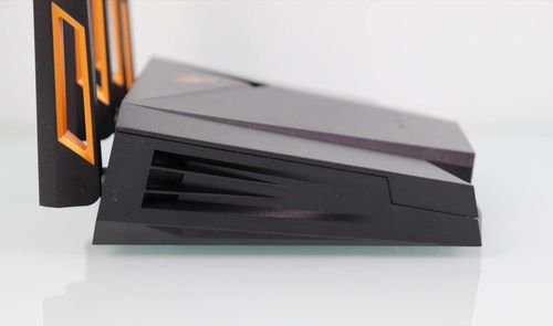 Vista lateral de un router ASUS TUF-AX4200 de color negro con rejillas de ventilación y antenas con detalles en naranja.