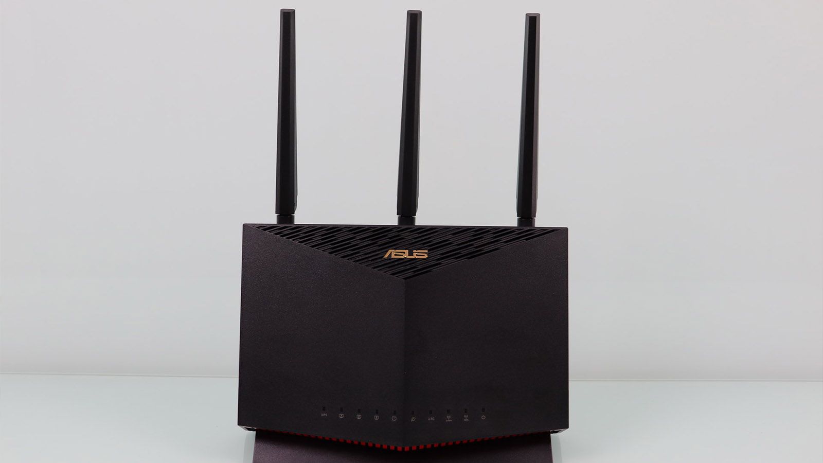 Router ASUS RT-AX86U visto de frente con sus tres antenas externas sobre un fondo neutro.