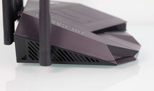 Vista lateral del router TUF-AX6000 con rejillas de ventilación y antenas externas en color oscuro.