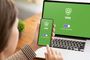 Usuario con un smartphone frente a un ordenador portátil, ambos mostrando una interfaz de conexión VPN activada sobre fondo verde.