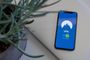 Teléfono móvil mostrando una aplicación de VPN activada junto a una planta y un portátil.