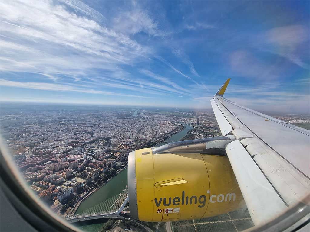 Vista aérea de Sevilla desde la ventanilla de un avión de Vueling sobrevolando el río Guadalquivir.