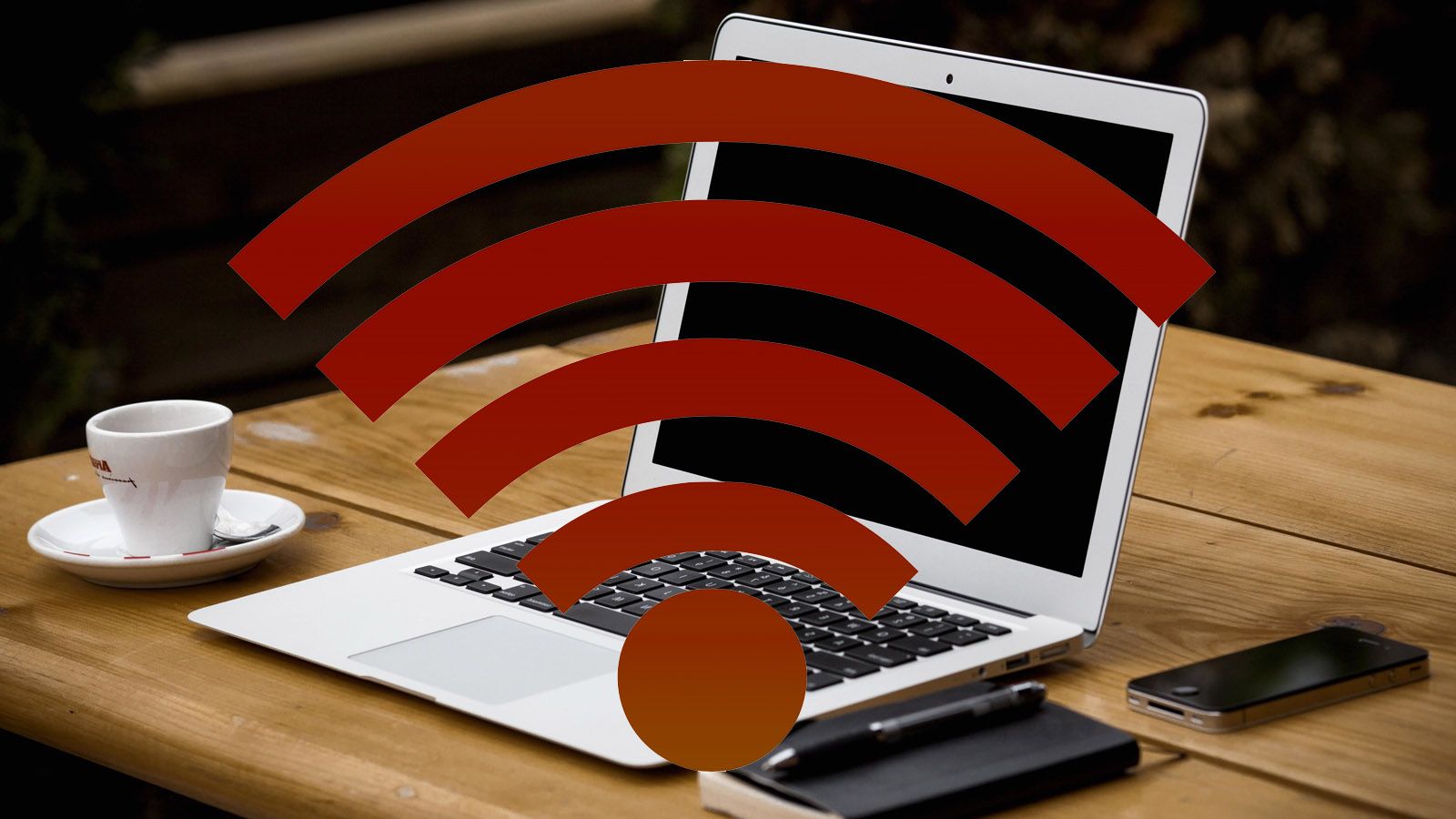 Ordenador portátil sobre una mesa de madera con un icono de señal Wi-Fi superpuesto en color rojo.